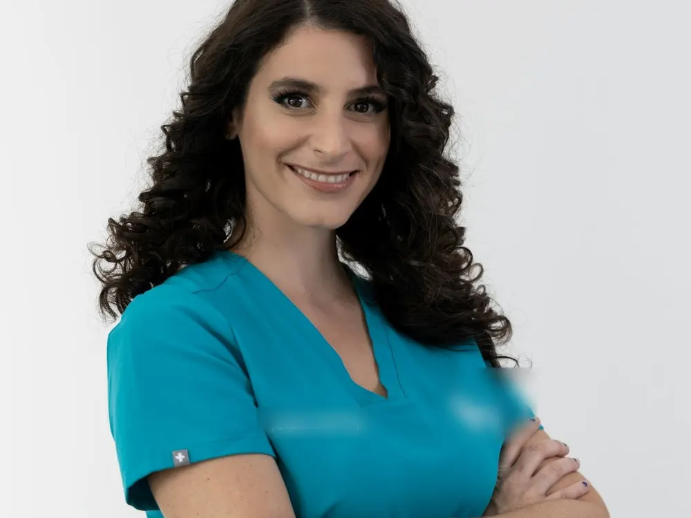 Professionnelle de santé souriante en tenue médicale turquoise, bras croisés